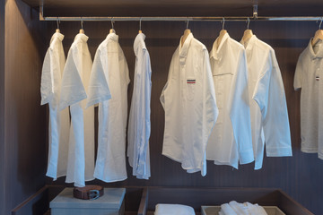 row of white shirts on rail in wooden closet