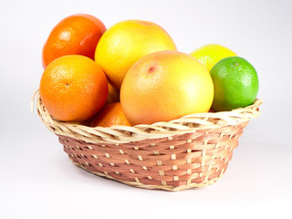 Basket of fresh colorful citrus fruits ready to be squeezed for healthy breakfast. Fruits are captured from different angles over white background.