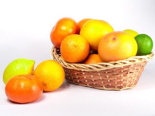 Basket of fresh colorful citrus fruits ready to be squeezed for healthy breakfast. Fruits are captured from different angles over white background.