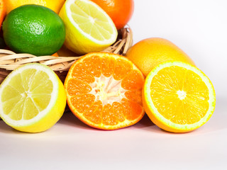 Basket of fresh colorful citrus fruits ready to be squeezed for healthy breakfast. Fruits are captured from different angles over white background.
