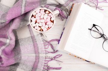 Naklejka premium Coffee cup, open book, glasses and plaid on white background. Reading book in home top view. Concept reading and hygge at cozy atmosphere