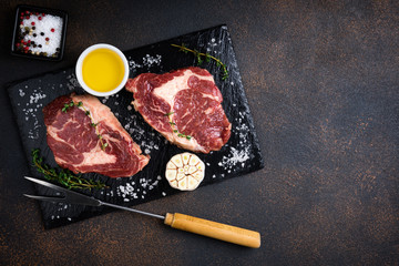 Raw meat. Raw beef steak on a cutting board with rosemary and spices, top view