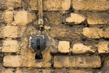 Old street light switch on a yellow brick wall