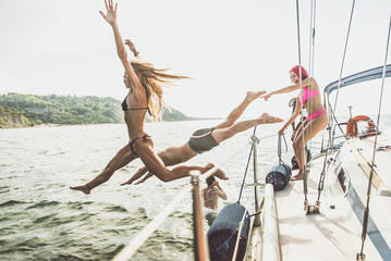 Fiends having fun on a sail boat and jump in the water