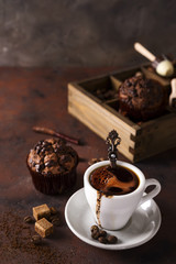 Cup of coffee with cooffee beans, wooden box with grains of coffee and spices, cupcake on a stone background
