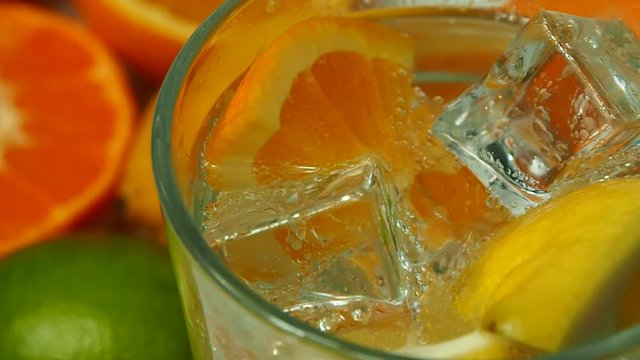 Fresh and juicy citrus fruits ice cubes are ready for cold soda. Bubbles are goes to the surface.
