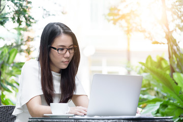 Beautiful asian attractive woman has working and typing on laptop computer for business marketing at coffee cafe in the morning with happy and relaxing time.