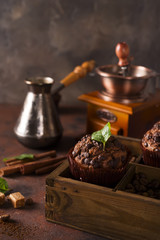 Chocolate muffins on a wooden box with grains of coffee and spices,