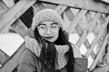 Portrait of brunette girl in gray scarf and hat, glasses at cold weather.
