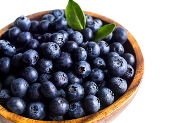 Juicy and fresh blueberries with green leaves on white bowl. Healthy eating