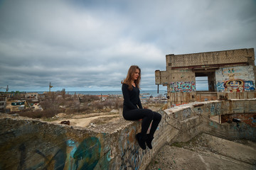 Fototapeta premium Young slim brunette on a ruins of abandoned building