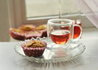 Homemade muffin and red juice in a glass cup on a white table. Close-up.