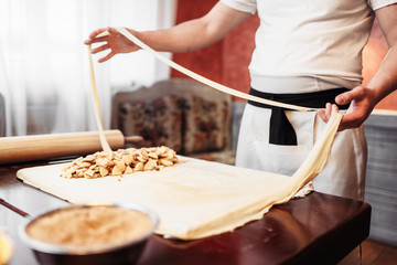 Male chef prepares dough for apple strudel