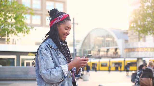 Black young woman typing on smart phone in Berlin