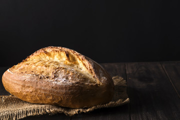 Bakery - gold rustic crusty loaves of bread and buns on black background.