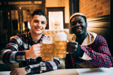 Close up of a two happy man friends drinking beer at bar or pub