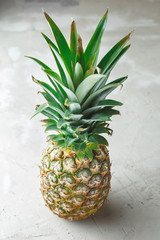 Fototapeta premium Whole pineapple fruit on grey concrete background