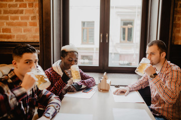 Happy smiling men friends clinking with beer mugs in pub