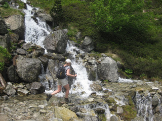Pireneje, Hiszpania - turystka przeskakuje przez strumień w Parku Narodowym Aigüestortes i Estany de Sant Maurici