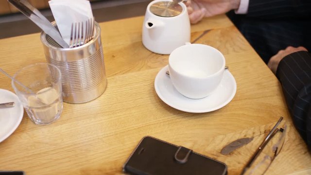A cup of tea being poured during a meeting at a coffee table