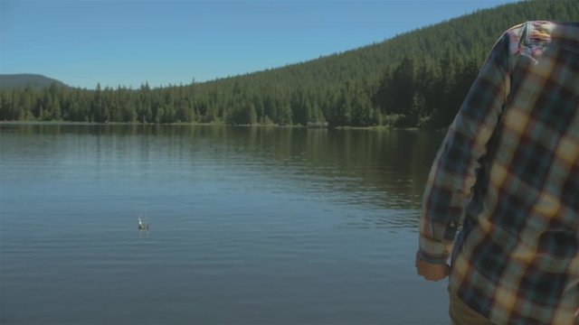 Young man skipping some rocks on a lake