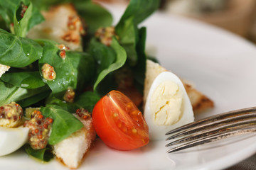 salad with quail egg, cherry tomato, crackers and corn salad on white plate