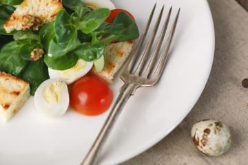 salad with quail egg, cherry tomato, crackers and corn salad on wooden background