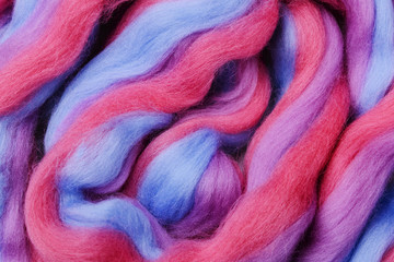Bright colored merino wool for felting and needlework, hobby. The stripes of pink, blue and violet color yarn folded into abstract pattern. Abstract art background
