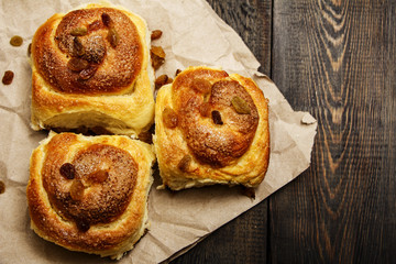 Freshly baked rolls with cinnamon with spices and raisins on parchment paper. View from above. Sweet homemade pastries. Close-up. Kanelbulle is a Swedish dessert.