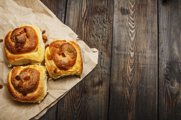 Freshly baked rolls with cinnamon with spices and raisins on parchment paper. View from above. Sweet homemade pastries. Close-up. Kanelbulle is a Swedish dessert.