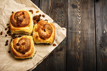 Freshly baked rolls with cinnamon with spices and raisins on parchment paper. View from above. Sweet homemade pastries. Close-up. Kanelbulle is a Swedish dessert.