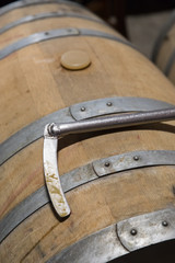 A baton for stirring wine on the lees resting on an oak barrel in a winery