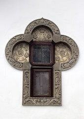 Window with wall ornaments of flowers that make it look like a Christian cross.
