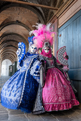 Obraz premium Dwie kobiety w maskach i ozdobnych niebiesko-różowych kostiumach stojące w pobliżu targu Rialto na karnawale w Wenecji (Carnivale di Venezia)