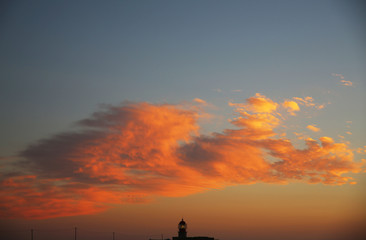 Fototapeta na wymiar Beautiful Orange Clouds with Lighthouse Silhouette in Europe