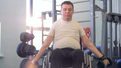 An adult handicapped man keeps lifting dumb-bells after a brief pause