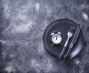 Grey alarm clock in empty plate. 