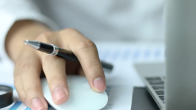 Human hands using a computer mouse on a desk, a businessman working