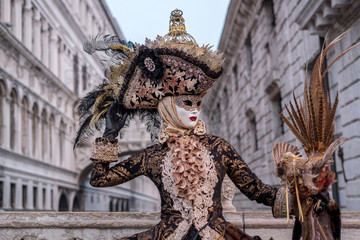 Woman in costume and mask, carrying feathered bird and birdcage, photographed during the Venice Carnival (Carnivale di Venezia)