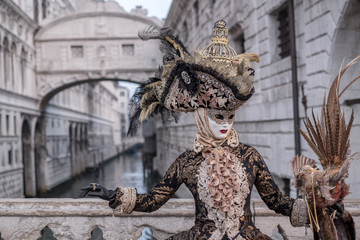 Fototapeta na wymiar Woman in costume and mask, carrying feathered bird and birdcage, photographed during the Venice Carnival (Carnivale di Venezia)
