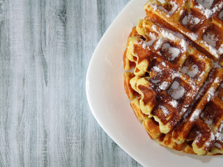 Belgian waffles in a white plate on a wooden table