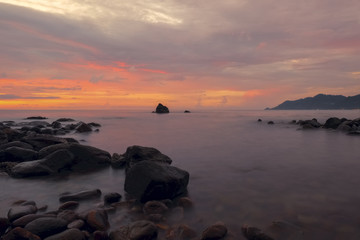 Fototapeta na wymiar Un couché de soleil sur une plage rocailleuse de Thaïlande