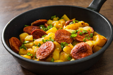 Roasted Potato and Sausage in frying pan on wooden table