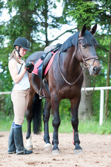 Young teenage girl owner with her stallion waiting for training