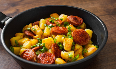 Roasted Potato and Sausage in frying pan on wooden table