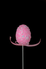 One pink easter egg on a stick with the ribbon in a form of hands wanted to hug.