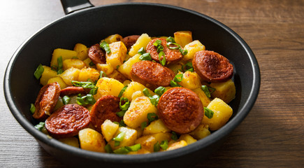 Roasted Potato and Sausage in frying pan on wooden table
