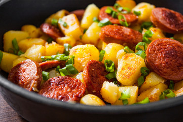 Roasted Potato and Sausage in frying pan on wooden table