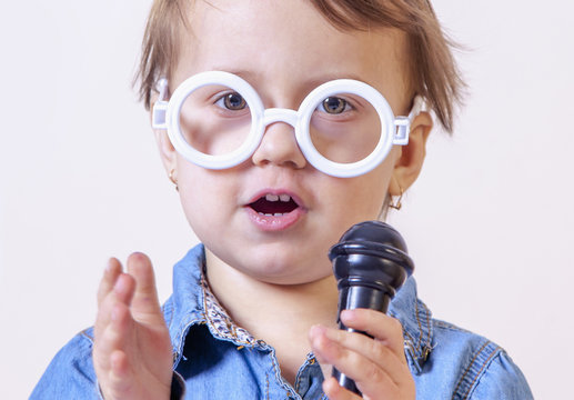The famous actress. Humorous photo of cute child girl singing with a microphone (Happy childhood, teaching singing, music, child development concept)