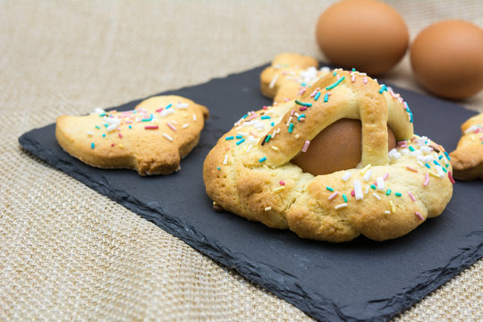 Horizontal View of Italian Baked Food Called Scarcella and Egg Baked Biscuits during Easter Celebrieties and on a Black Square Slate Plate on Blur Background